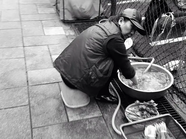 In this picture I can see there is a woman sitting and she is mixing something in the bowl and...
