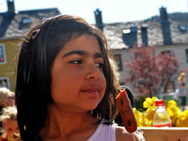 In the center of the image, we can see a kid holding a food item and in the background, there are...