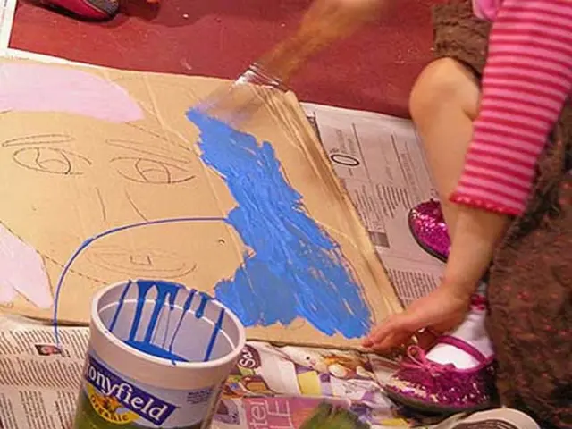 In this image there is a paint box with paint in it, paint brush , cardboard sheet on the newspaper...